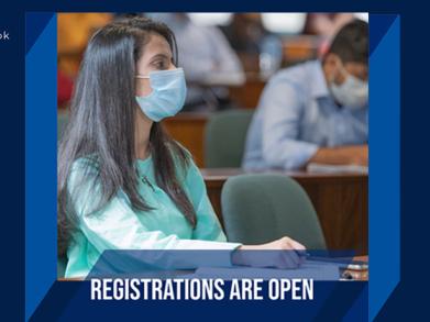 A girl wearing a light green shirt and a mask sitting in a classroom